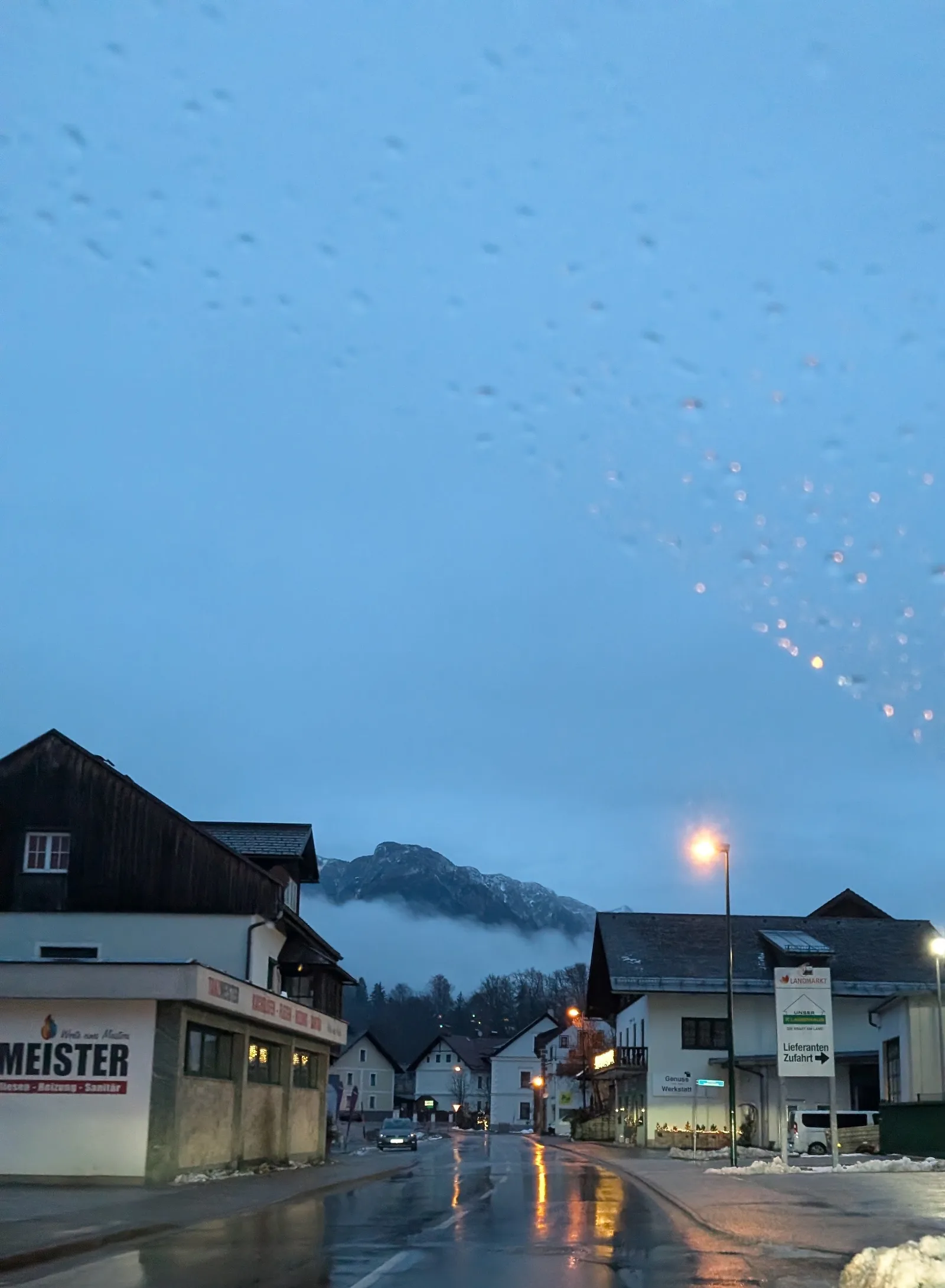 Bahnhofstraße in Bad Aussee in der Abenddämmerung, links das Geschäft mit dem Schriftzug Tanzmeister, dahinter die Berge